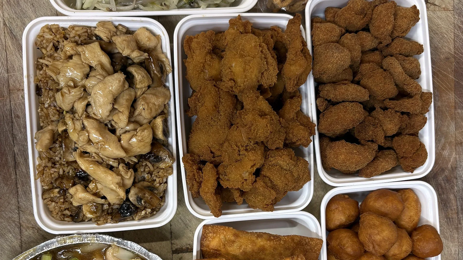 A takeout order of chicken balls, egg rolls, chow mein and mixed vegetables